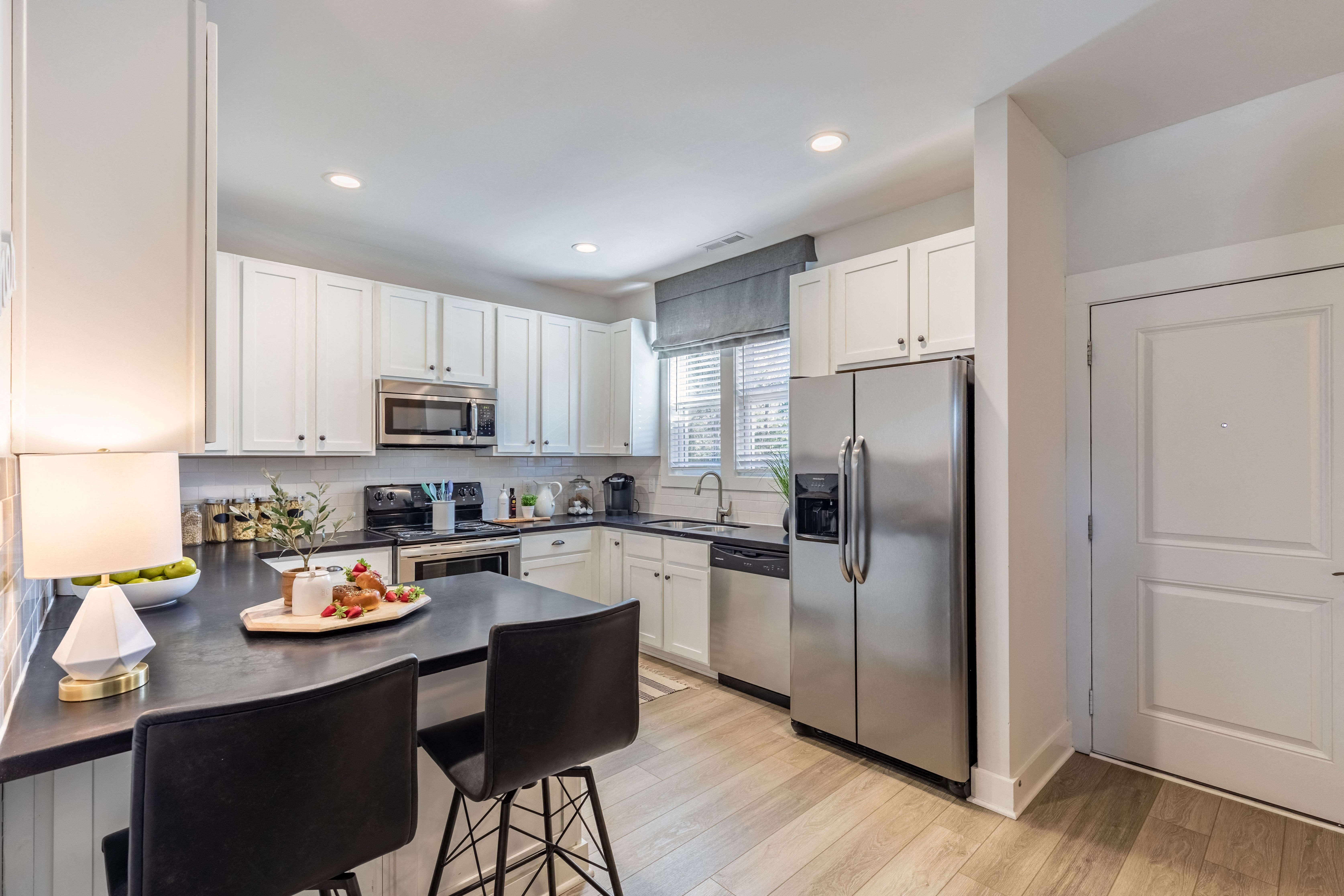 Townhouses in Wilmington NC - Myrtle Landing - Kitchen with White Cabinets, a Breakfast Bar, Wood-Style Flooring, and Stainless-Steel Appliances